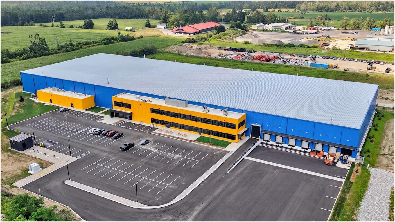 Aerial view of the Hörmann North America manufacturing facility in Oro-Medonte, Ontario — blue warehouse with a yellow two-storey office block and loading docks