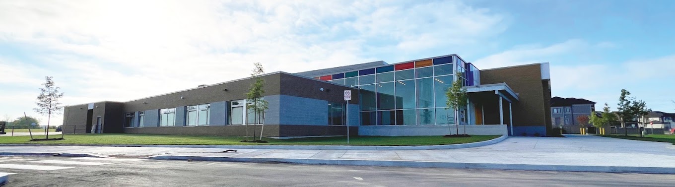 Exterior of Wasaga Beach Public School — single-storey brick building with a colourful glass curtain wall entrance